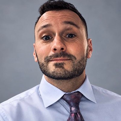 Headshot of Michael P. Goodman in a light blue dress shirt and purple tie