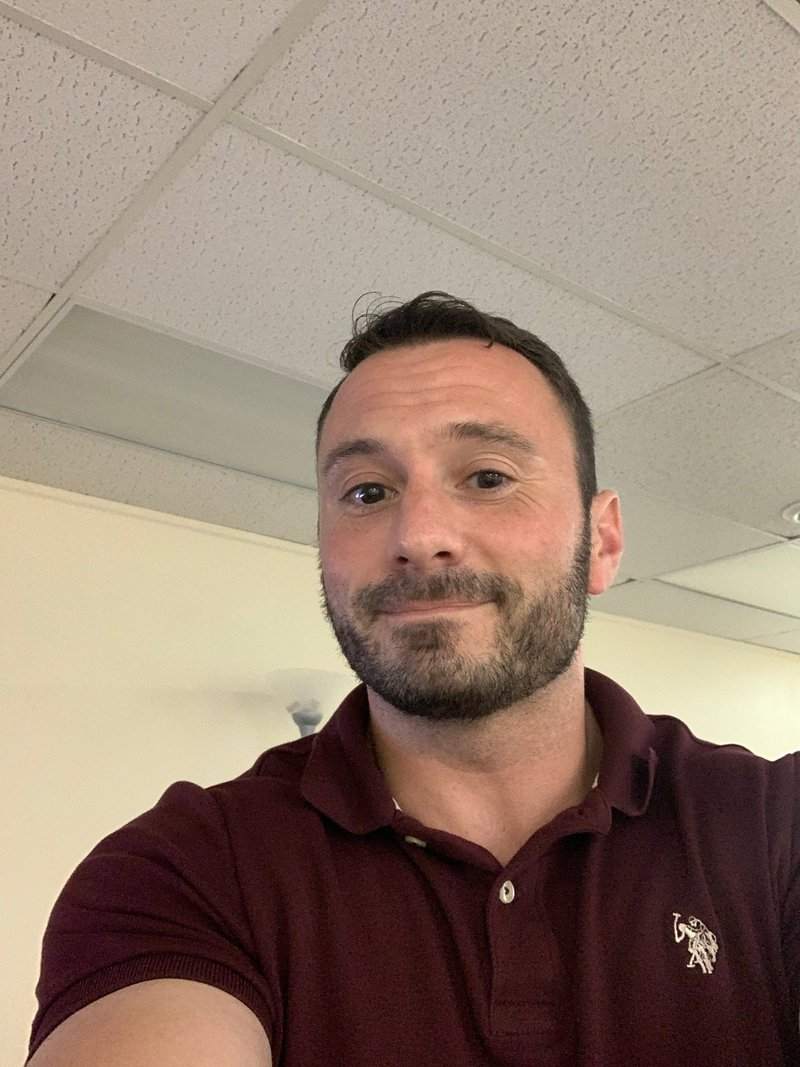 Michael P. Goodman in a maroon polo shirt looking at the camera in an office